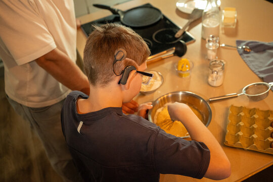 Young boy with hearing aid  mixing batter in kitchen