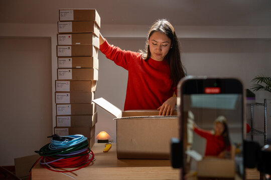 Woman organizing product shipment with camera recording