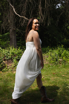 Beautiful woman in white dress walking under the old trees