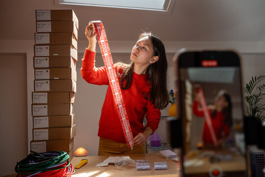 Woman Measuring Ribbon in a Workspace With Boxes and Tools