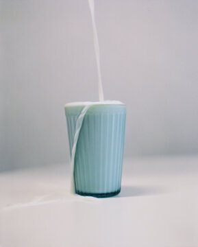 Glass of milk, pouring in a glass cup with splashes on table