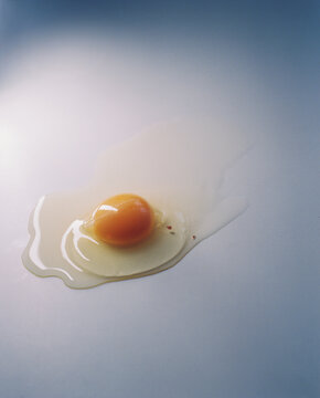 A broken egg drips slowly down the table.