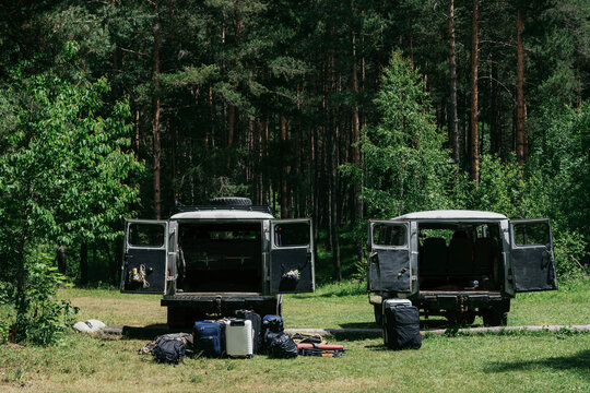 Camping gear and vehicles near forest location for outdoor adventure
