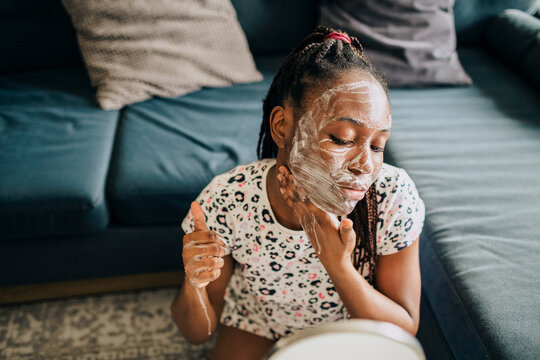 Home portrait of african american woman washing skin with foam