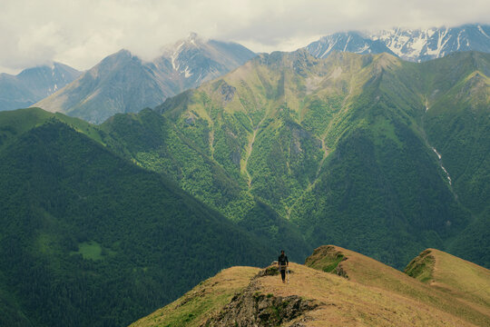 Hiker explores mountain range at high altitude during cloudy day
