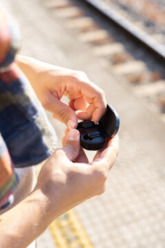 Traveler pulls out a wireless earphone in a train station