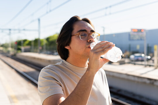 Young man drinking water from a plastic bottle on a sunny day