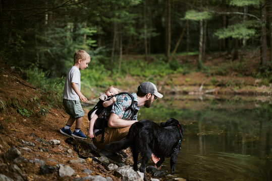 family with dog taking a hiking break by a pond in the woods
