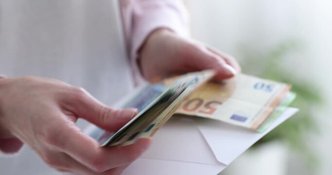 Woman opening envelope with euro banknotes indoors, closeup