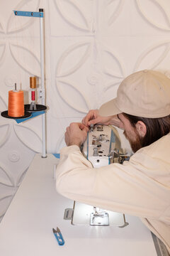 The guy sews clothes in the creative space.