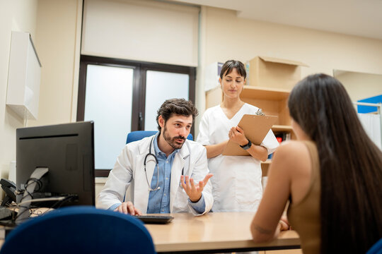 Doctor explaining diagnosis to patient with nurse taking notes