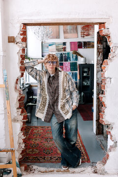 Female stands in doorway of an open space with exposed brick