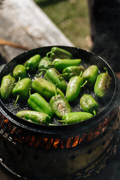Green chili peppers roasting on open flame grill