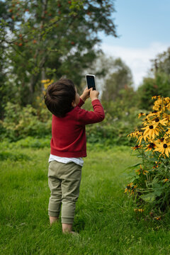 Child taking photo with smartphone in garden