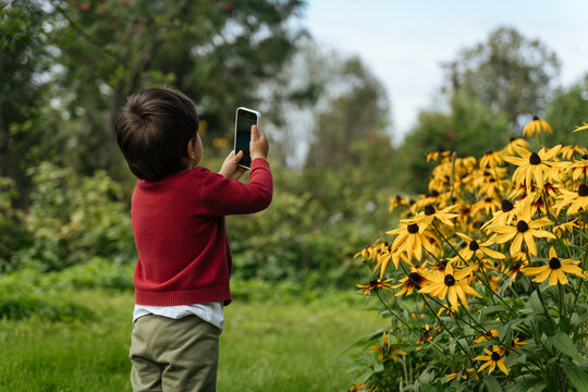 Child taking a photo of yellow flowers with smartphone