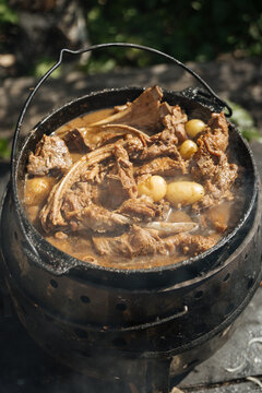 Meat and potatoes cooking in outdoor pot