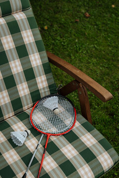 Badminton rackets and shuttlecocks on plaid outdoor chair