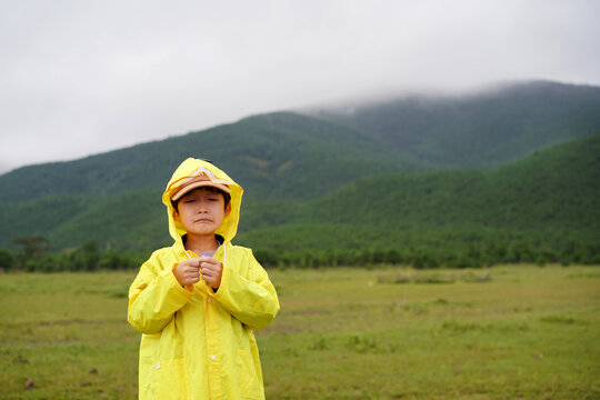 A Chinese boy in a raincoat with a sad expression