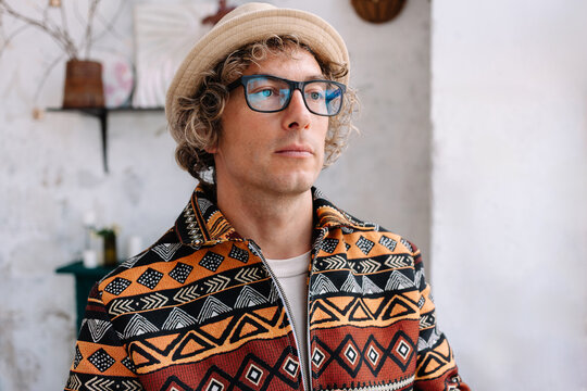 Man with curly hair and glasses in a patterned jacket