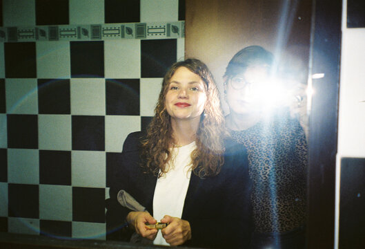 Friends Smiling in a Mirror Selfie at a Colorful Location