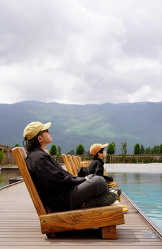 Chinese father and son sits on a lounge chair 