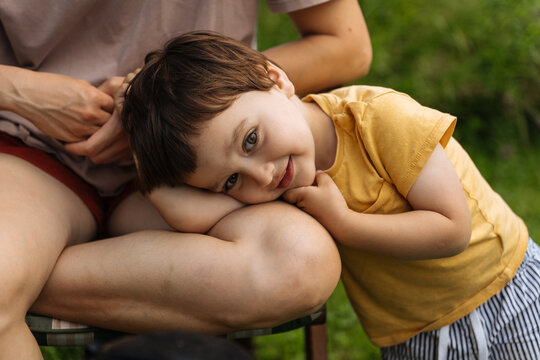 Smiling child resting head on adult's knee
