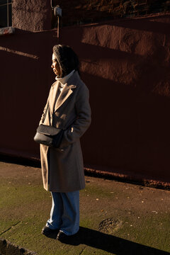 Thoughtful Asian Woman on City Sidewalk During Sunset in Winter