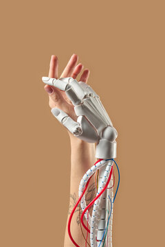 Robot prosthetic and human hand on beige background