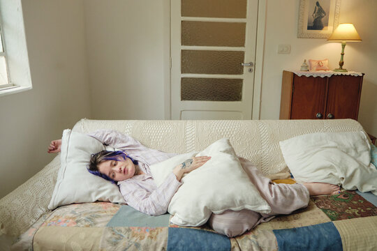Young person looking introspective lying down in the couch
