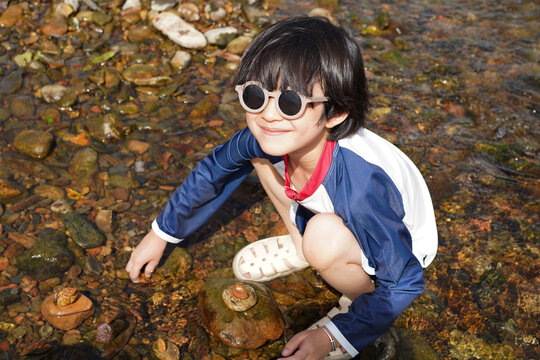Chinese boy plays in a mountain stream.