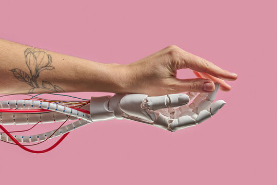 Human and robot hands contact on pink background