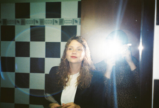 Young Woman Smiles in Bathroom With Flash Photography