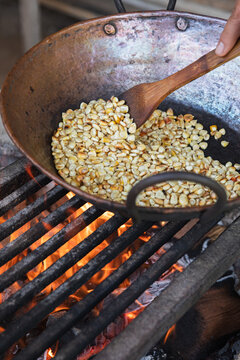 Roasting corn kernels over open flames in copper pan