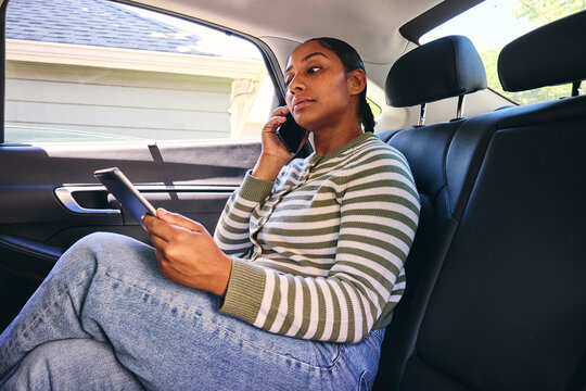 Woman talking on a phone with ipad in a car