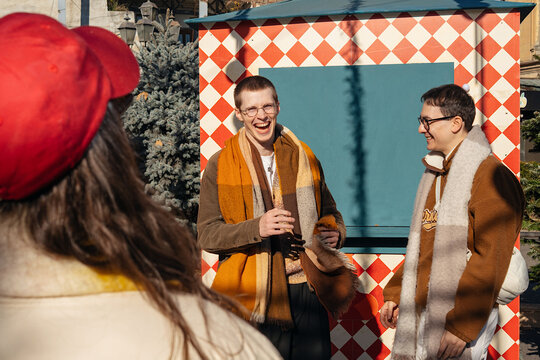 Friends share laughter outdoors in winter sun near trees