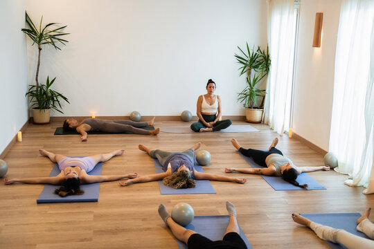 Group yoga practice in a bright studio. Everyone is lying on the floor