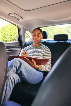 Young woman making notes in a car 