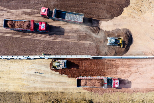 Aerial earthmoving construction site with dump trucks