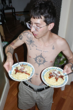 Person Holds Two Plates of Pasta 