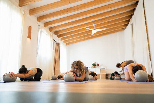 People practice stretching with exercise balls in a studio
