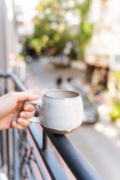 Hand holding a ceramic mug on a balcony