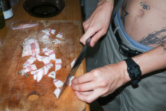 Anonymous person cutting bacon on Wooden Board