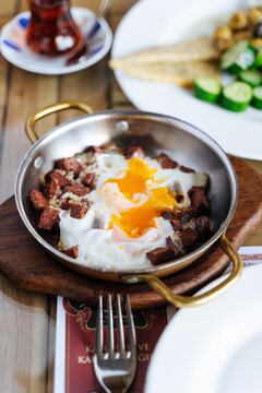 Fried eggs with sausage served in copper pan