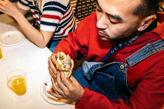 Man eating loaded hamburger at fast food dinner