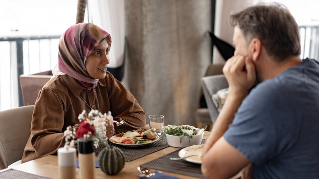Muslim Couple Enjoying Dinner Conversation in Restaurant