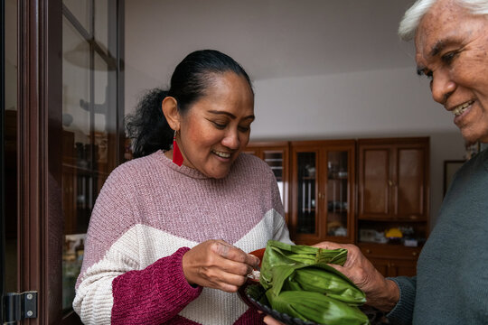 Intergenerational family joy while preparing Indonesian rice parcels