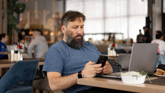 Middle-Aged Man Working on Laptop in Busy Restaurant