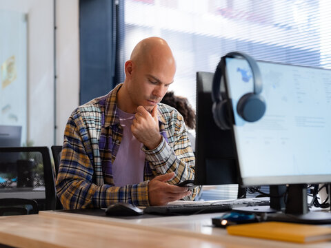 Thoughtful man using smartphone at office 