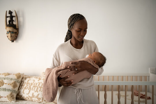 Young mother is lulling baby in bedroom 