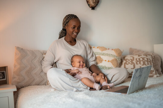 Happy baby watching cartoons with mother on laptop 